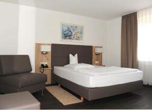 a bedroom with a large bed and a chair at Hotel Hamann in Balingen