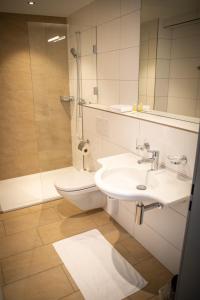 a bathroom with a sink and a shower and a toilet at Hotel Schützenhaus in Uznach