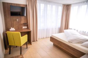 a bedroom with a bed and a desk and a yellow chair at Hotel Schützenhaus in Uznach