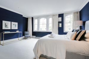 um quarto com paredes azuis e uma cama branca em Chic Wandsworth Home with Patio by UndertheDoormat em Londres