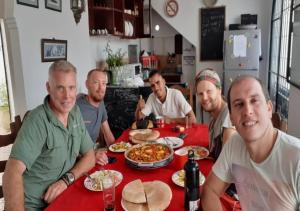 un grupo de hombres sentados en una mesa comiendo comida en The Medina Hostel, en Tánger
