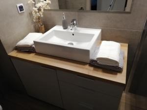 un lavabo con toallas en una encimera de madera en Papaver Apartament, en Zielona Góra 14 fotos más