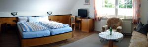 a bedroom with a bed and a desk with a tv at Pension Am Wiesengrund in Detern