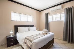 a bedroom with a large bed and two windows at Arebbusch Travel Lodge in Windhoek