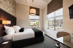 a hotel room with a bed and two windows at Boutique Hotel Notting Hill in Amsterdam