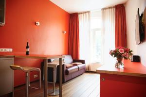 アムステルダムにあるプリンセンフイスのオレンジ色の壁のリビングルーム(テーブル、ソファ付)
