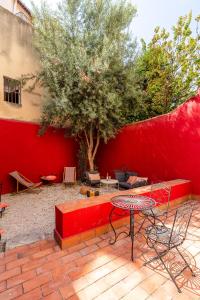 un banc rouge, une table et un arbre dans l'établissement LE PANIER ENCHANTÉ - Suites & Loft - Terrasse et patio au dessus du Vieux Port, à Marseille