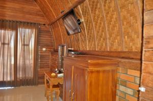 a room with a wooden wall with a table and a television at Surya Chandra Beach Bungalow in Nusa Penida