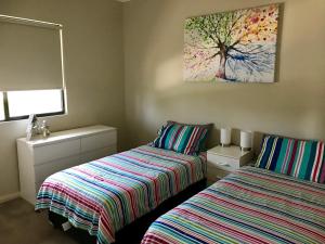 a bedroom with two beds and a tree painting on the wall at Coastal Paradise Jurien Bay in Jurien Bay