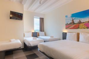 
a hotel room with two beds and a painting on the wall at Maxhotel Amsterdam Airport Schiphol in Hoofddorp
