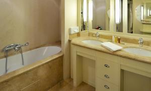 La salle de bains est pourvue de 2 lavabos, d'une baignoire et d'un miroir. dans l'établissement Le Grand Hôtel - Domaine De Divonne, à Divonne-les-Bains