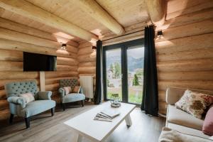 a living room in a log cabin with a large window at Clofers Leisure Lodges Jenig in Jenig