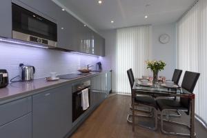 ロンドンにあるDeluxe Central London Apartmentのキッチン(ガラステーブル、黒い椅子付)