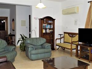 a living room with a couch and chairs and a tv at Villa Dioni in Coral Bay