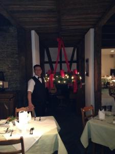 a man standing next to a table in a restaurant at Hotel Alte Linden in Altena