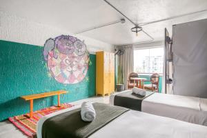 Habitación con 2 camas y una pintura en la pared. en Selina Miraflores Lima, en Lima