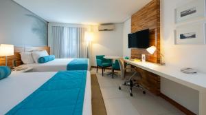 Habitación de hotel con 2 camas y escritorio en Best Western Premier Maceió en Maceió