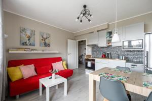 salon i kuchnia z czerwoną kanapą i stołem w obiekcie Gama Home Kondratowicza18 w Warszawie