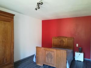 Un dormitorio con una cama y una pared roja. en Maison à la ferme, en Saint-Aubin-le-Monial