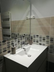Un lavabo blanco en un baño con espejo. en Maison à la ferme, en Saint-Aubin-le-Monial