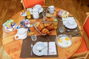 - une table avec petit-déjeuner composé d'œufs et de croissants dans l'établissement Hôtel du Vigan, à Albi