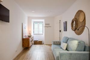 a living room with a blue couch and a television at Charming Studio in Lisbon's center! in Lisbon