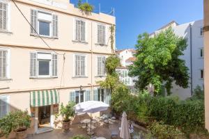 un bâtiment avec un parasol, des chaises et un arbre dans l'établissement Forville, à Cannes