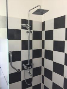 łazienkę z prysznicem wyłożoną czarno-białymi kafelkami. w obiekcie Jolie halte normande w mieście Balines