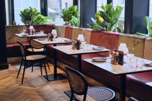 a restaurant with tables and chairs and plants at Le Monde Hotel in Edinburgh