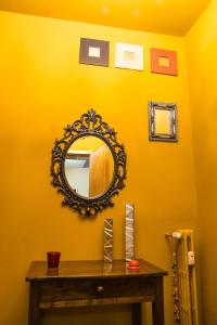 a mirror on a yellow wall with a wooden table at CameLia in Ivrea
