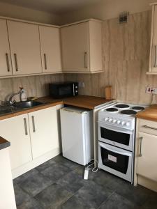 a kitchen with white cabinets and a stove top oven at Sheil Suites in Liverpool