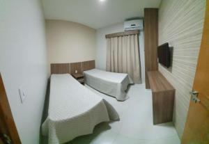 a small room with two beds and a television at Paradise Temporada Cobertura 4 Quartos com Jacuzzi e Churrasqueira no Thermas Paradise - Rio Quente in Rio Quente +53 photos