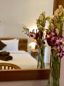 zwei Vasen voller Blumen auf einem Tisch neben einem Bett in der Unterkunft The Hidden Bali Inn in Ubud