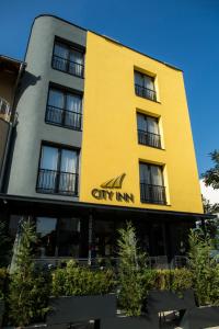 un edificio amarillo con un letrero de la posada de la ciudad en City Inn, en Pristina