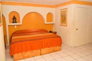 a bedroom with a bed with an orange blanket at HOTEL BAEZA in Delicias