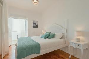a white bedroom with a bed with green and white pillows at MyPlaceLisbon - Tágides River View in Lisbon