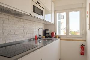 a white kitchen with a sink and a window at MyPlaceLisbon - Tágides River View in Lisbon