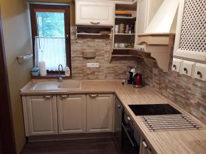 a kitchen with white cabinets and a sink and a window at Apartman Naji - Tale in Tale