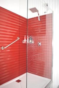y baño con ducha y pared roja. en Must Love Dogs B&B & Self Contained Cottage, en Rutherglen