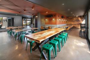 un restaurante con mesas de madera y taburetes verdes en Waypoint Hotel en Bend