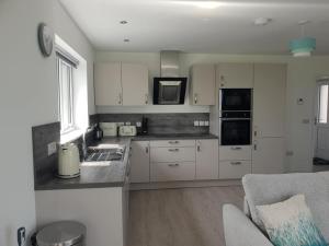 a kitchen with white cabinets and a sink and a couch at Cottiscarth Cottages in Finstown