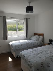 two beds in a bedroom with a window at Cottiscarth Cottages in Finstown