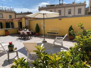un patio con sillas, sombrilla y mesas en Art terrace, en Nápoles