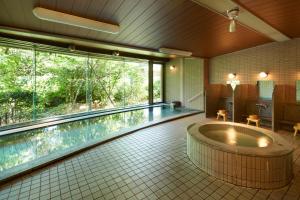 baño grande con bañera y piscina en HILLTOP RESORT FUKUOKA - Former Agora Fukuoka Hilltop Hotel & Spa, en Fukuoka