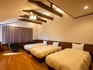 a room with three beds and a ceiling fan at Villa Ensoleille in Fujikawaguchiko