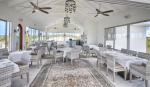 a dining room with white tables and chairs and windows at Neptune Villas in Five Cays Settlement