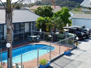 a swimming pool with a fence next to a house at Mana-Nui Motel in Whitianga
