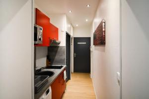 eine Küche mit orangefarbenen Schränken und einem weißen Kühlschrank in der Unterkunft Petit appartement douillet très bien situé in Biarritz