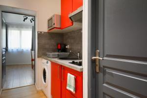 - une cuisine avec des placards rouges et un lave-linge dans l'établissement Petit appartement douillet très bien situé, à Biarritz