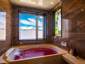La salle de bains est pourvue d'une grande baignoire et d'une fenêtre. dans l'établissement Villa Ensoleille, à Fujikawaguchiko